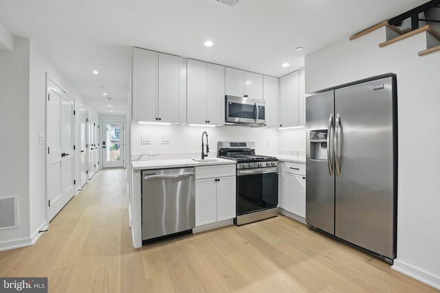 3802 T St NW, Washington, DC 20007 - kitchen featuring appliances with stainless steel finishes, light wood-style floors, white cabinets, a sink, and recessed lighting