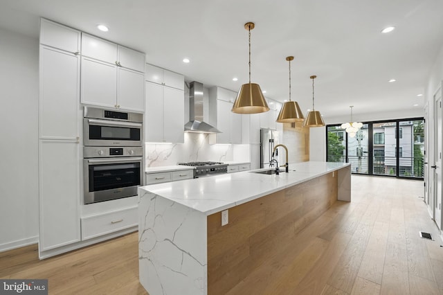 3802 T St NW, Washington, DC 20007 - kitchen with wall chimney exhaust hood, a sink, light wood finished floors, stainless steel appliances, and white cabinets