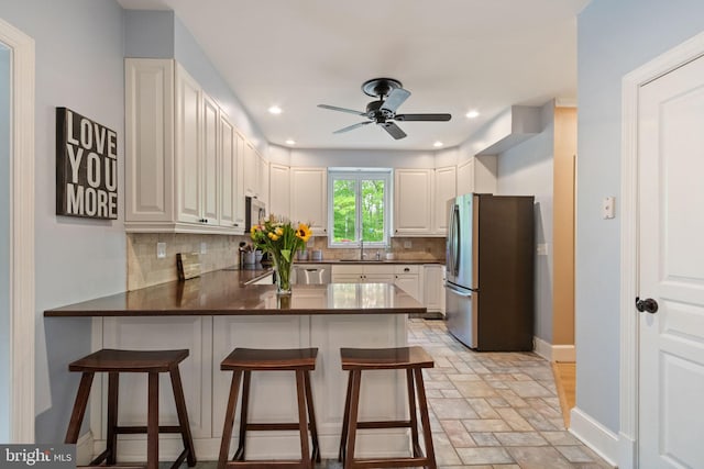 10108 Rockinghorse Ln, Spotsylvania, VA 22553 - kitchen with appliances with stainless steel finishes, a sink, a peninsula, decorative backsplash, and ceiling fan