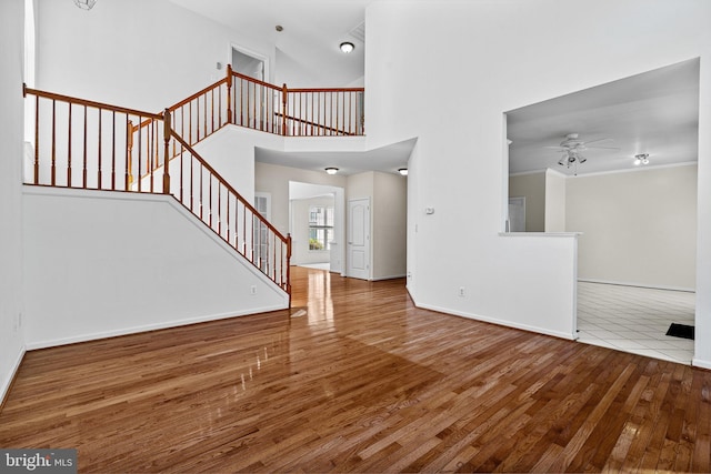 1903 Scottish Isle Ct, Abingdon, MD 21009 - unfurnished living room featuring ceiling fan, wood finished floors, stairs, baseboards, and a towering ceiling