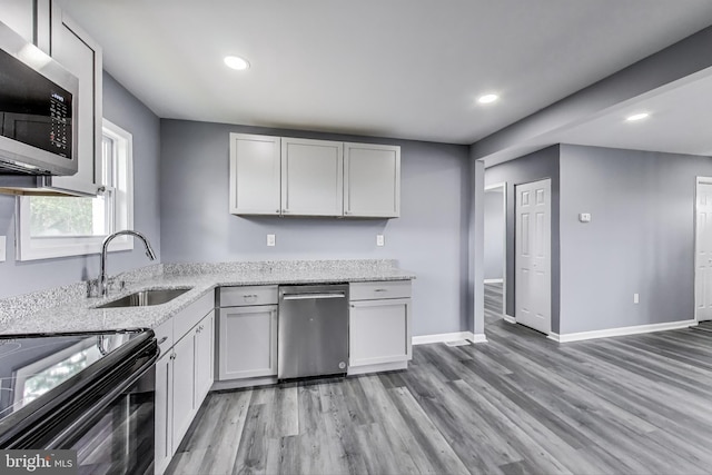 2500 Gehb Ave, Baltimore, MD 21227 - kitchen featuring appliances with stainless steel finishes, a sink, light wood-type flooring, light stone counters, and baseboards