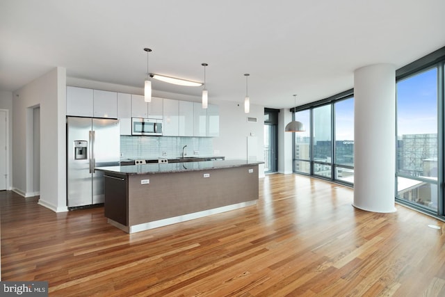2101 Market St Unit 902, Philadelphia, PA 19103 - kitchen with stainless steel appliances, white cabinetry, an island with sink, light wood-type flooring, and decorative backsplash