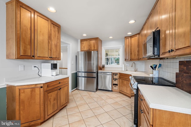 4301 Ivanhoe Pl, Alexandria, VA 22304 - kitchen featuring stainless steel appliances, brown cabinets, a sink, light countertops, and backsplash