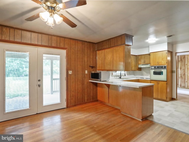 193 Chevy Ln, Berkeley Springs, WV 25411 - kitchen featuring white appliances, a peninsula, brown cabinetry, light countertops, and under cabinet range hood
