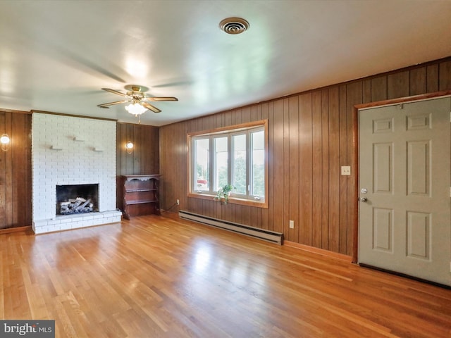 193 Chevy Ln, Berkeley Springs, WV 25411 - unfurnished living room with a baseboard radiator, a ceiling fan, wood finished floors, a fireplace, and wooden walls