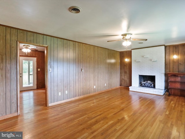 193 Chevy Ln, Berkeley Springs, WV 25411 - unfurnished living room featuring ceiling fan, wood finished floors, a brick fireplace, wood walls, and ornamental molding