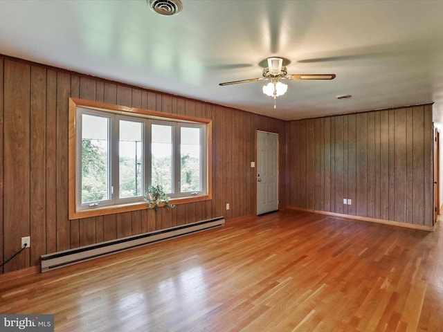 193 Chevy Ln, Berkeley Springs, WV 25411 - unfurnished room with a baseboard heating unit, wood finished floors, a ceiling fan, wooden walls, and baseboards
