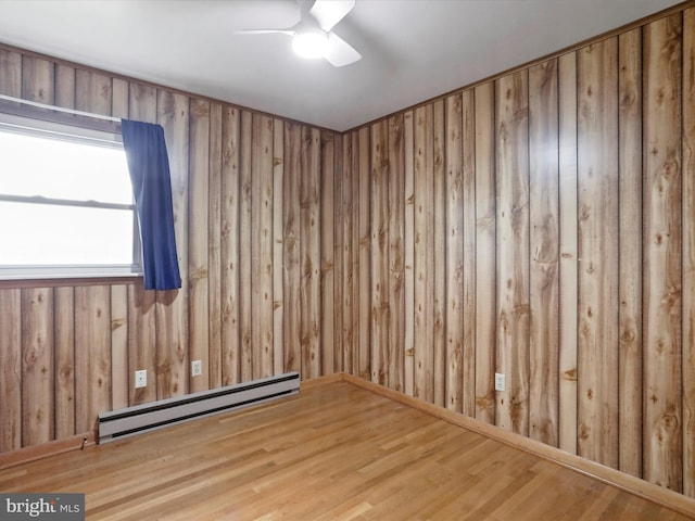 193 Chevy Ln, Berkeley Springs, WV 25411 - spare room featuring a baseboard radiator, a ceiling fan, wood finished floors, and wooden walls