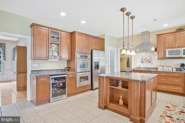 927 Brick Manor Cir, Silver Spring, MD 20905 - kitchen featuring appliances with stainless steel finishes, wall chimney range hood, wine cooler, brown cabinetry, and light stone counters