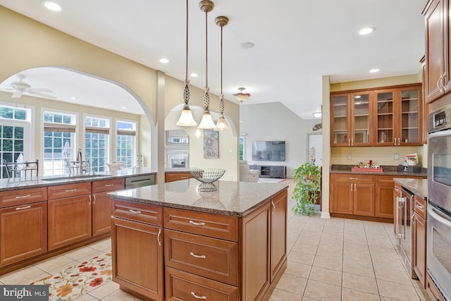 927 Brick Manor Cir, Silver Spring, MD 20905 - kitchen with a sink, light tile patterned floors, arched walkways, a kitchen island, and brown cabinetry