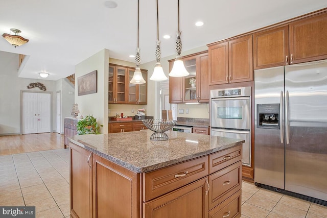 927 Brick Manor Cir, Silver Spring, MD 20905 - kitchen with appliances with stainless steel finishes, light tile patterned floors, brown cabinets, a kitchen island, and light stone countertops