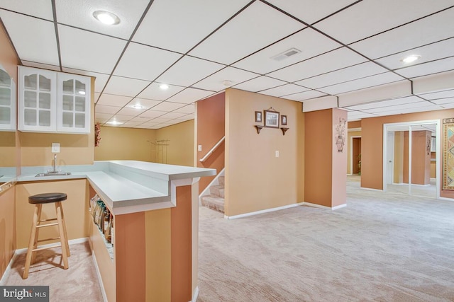 927 Brick Manor Cir, Silver Spring, MD 20905 - kitchen with light colored carpet, a peninsula, light countertops, a sink, and a paneled ceiling