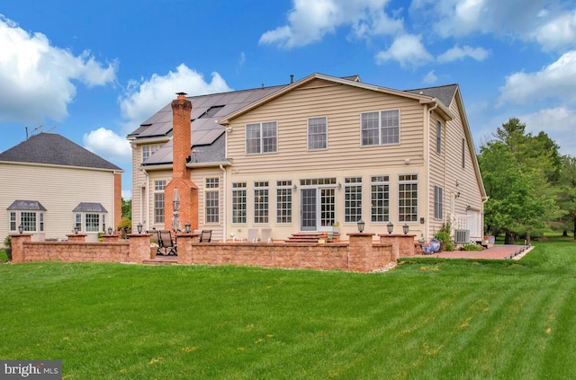 927 Brick Manor Cir, Silver Spring, MD 20905 - back of house with a patio area, a lawn, solar panels, and a chimney