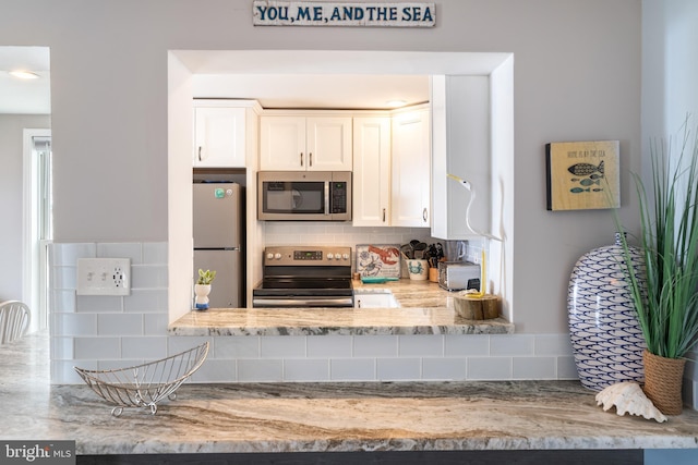 183 Jamestown Rd Unit 10, Ocean City, MD 21842 - kitchen featuring stainless steel appliances, decorative backsplash, white cabinets, and light stone countertops