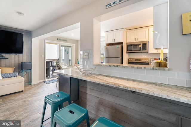 183 Jamestown Rd Unit 10, Ocean City, MD 21842 - kitchen with stainless steel appliances, light stone counters, tasteful backsplash, light wood finished floors, and white cabinetry