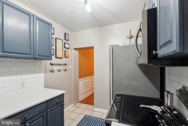 2326 E Boston St, Philadelphia, PA 19125 - kitchen featuring blue cabinets, stainless steel microwave, light tile patterned floors, and tasteful backsplash