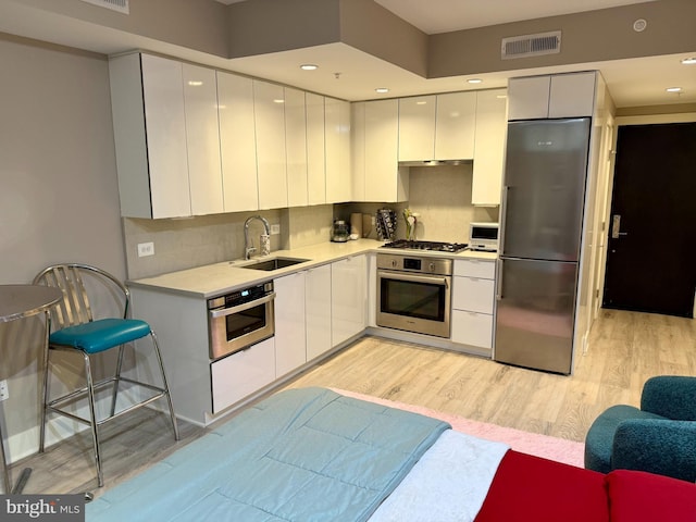 1311 13th St NW Unit T05, Washington, DC 20005 - kitchen with stainless steel appliances, a sink, modern cabinets, light wood-style floors, and white cabinets