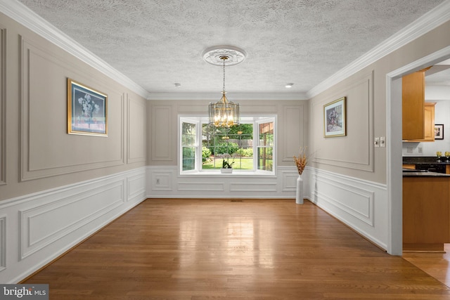 17220 Larosa Dr, Rockville, MD 20855 - unfurnished dining area with a decorative wall, a chandelier, light wood-style floors, a textured ceiling, and crown molding