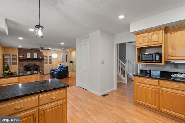 17220 Larosa Dr, Rockville, MD 20855 - kitchen featuring black microwave, light wood-type flooring, a brick fireplace, a ceiling fan, and open floor plan