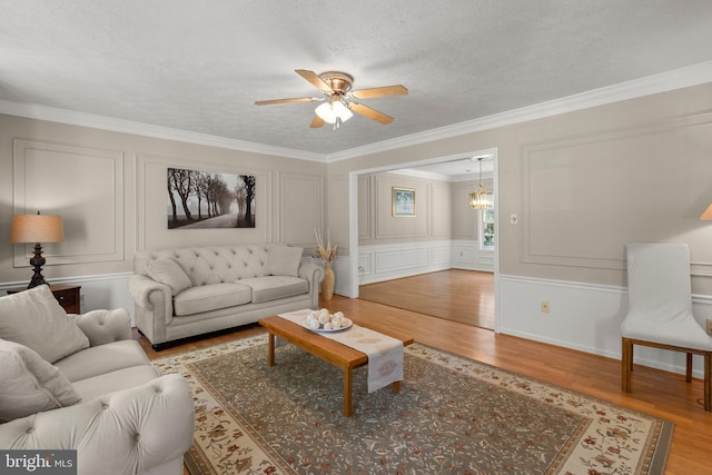 17220 Larosa Dr, Rockville, MD 20855 - living room featuring wood finished floors, a textured ceiling, ceiling fan, ornamental molding, and a decorative wall