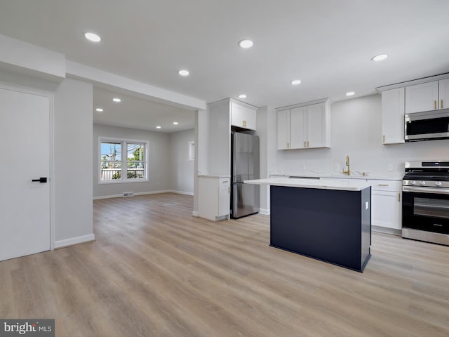 7907 Wallace Rd, Dundalk, MD 21222 - kitchen featuring appliances with stainless steel finishes, a sink, light countertops, light wood-style flooring, and a kitchen island
