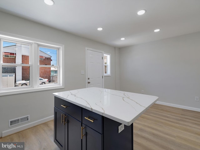 7907 Wallace Rd, Dundalk, MD 21222 - kitchen featuring light wood-type flooring, baseboards, recessed lighting, a kitchen island, and light stone countertops
