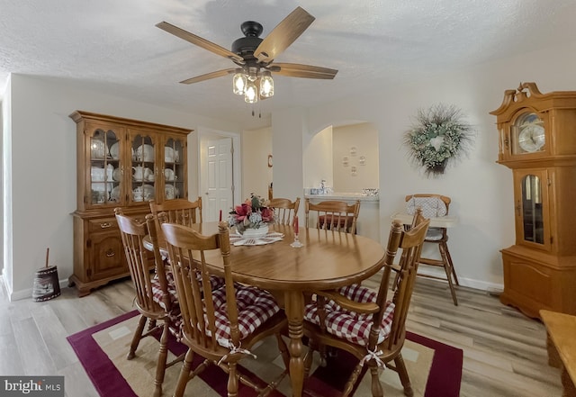 6165 Hawthorne Rd, La Plata, MD 20646 - dining area featuring light wood-type flooring, ceiling fan, arched walkways, a textured ceiling, and baseboards