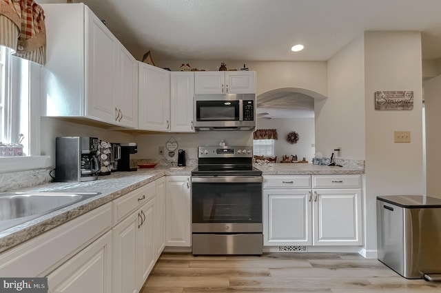 6165 Hawthorne Rd, La Plata, MD 20646 - kitchen with stainless steel appliances, white cabinets, arched walkways, and light countertops