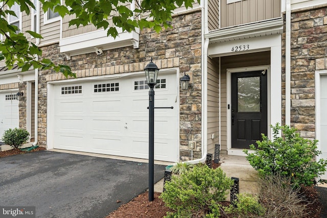 42533 Benfold Sq, Brambleton, VA 20148 - property entrance with stone siding, a garage, driveway, and board and batten siding