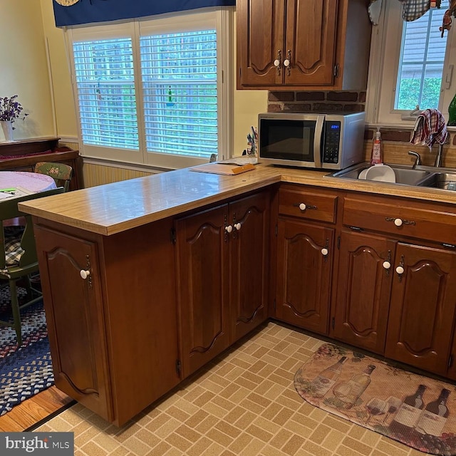 603 Jefferson Blvd, Reading, PA 19609 - kitchen with stainless steel microwave, light countertops, a peninsula, a sink, and brick patterned flooring