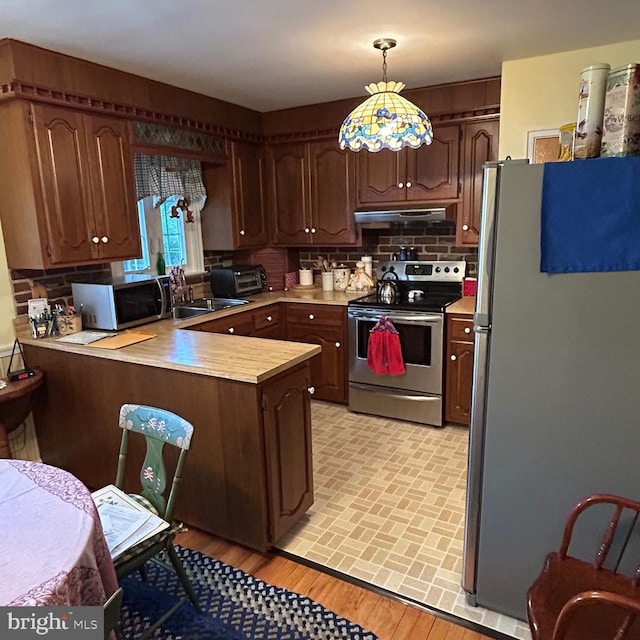 603 Jefferson Blvd, Reading, PA 19609 - kitchen with appliances with stainless steel finishes, a peninsula, under cabinet range hood, light countertops, and backsplash