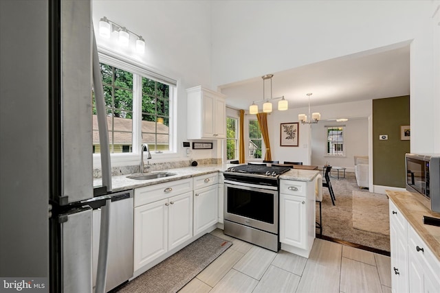 5804 Woodcrest Ave, Baltimore, MD 21215 - kitchen featuring a sink, appliances with stainless steel finishes, a peninsula, a chandelier, and white cabinets