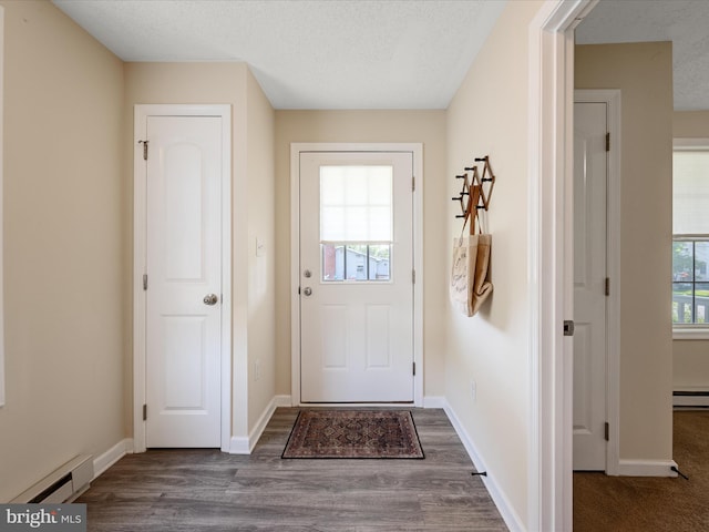 111 S Buchannan St, Ranson, WV 25438 - doorway to outside featuring a baseboard radiator, dark wood-style floors, baseboards, and a textured ceiling