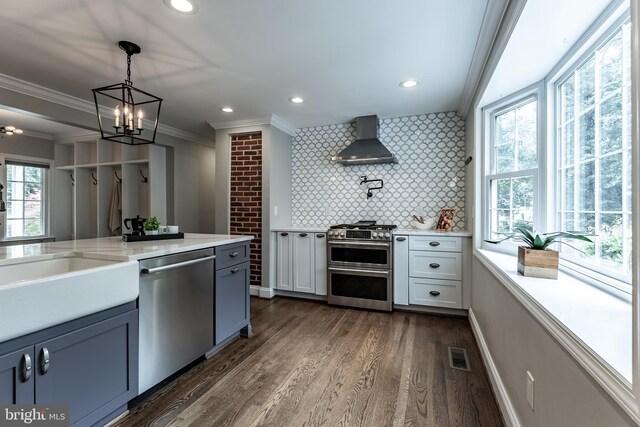 5632 Glenwood Dr, Alexandria, VA 22310 - kitchen featuring wall chimney range hood, stainless steel appliances, ornamental molding, a chandelier, and dark wood-style flooring