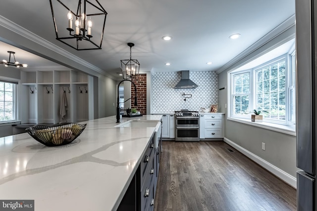 5632 Glenwood Dr, Alexandria, VA 22310 - kitchen featuring range with two ovens, wall chimney range hood, a chandelier, crown molding, and light stone countertops
