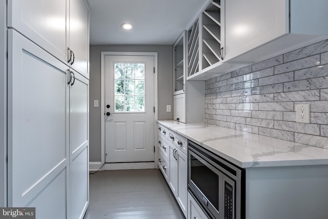 5632 Glenwood Dr, Alexandria, VA 22310 - kitchen with stainless steel microwave, decorative backsplash, glass insert cabinets, recessed lighting, and white cabinetry