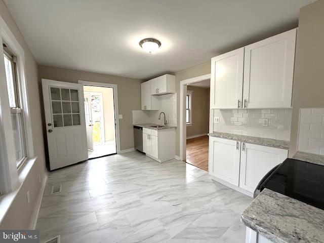 2222 Spruce St, Ewing, NJ 08638 - kitchen with a sink, stainless steel dishwasher, decorative backsplash, white cabinets, and light stone countertops
