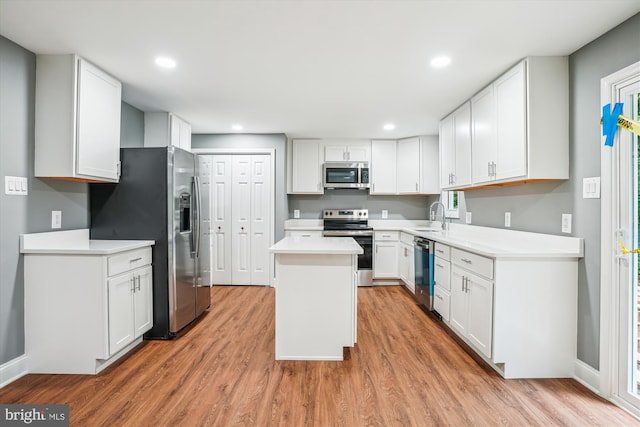 5311 Cove View Dr, Saint Leonard, MD 20685 - kitchen with appliances with stainless steel finishes, a sink, light wood finished floors, a center island, and white cabinets