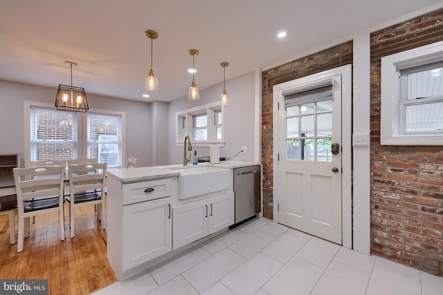 616 New Holland Ave, Lancaster, PA 17602 - kitchen with dishwasher, a peninsula, white cabinets, hanging light fixtures, and brick wall