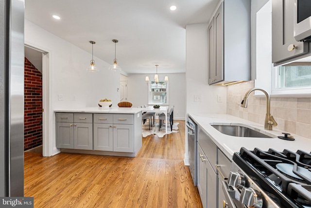 1604 Crittenden St NE, Washington, DC 20017 - kitchen featuring gray cabinetry, stainless steel appliances, light wood-style flooring, tasteful backsplash, and decorative light fixtures