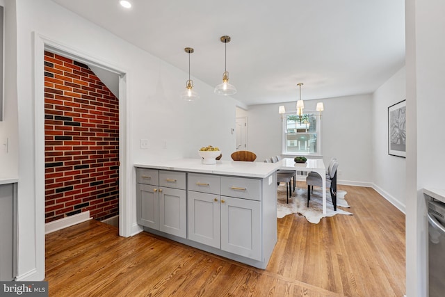 1604 Crittenden St NE, Washington, DC 20017 - kitchen with gray cabinets, light wood-type flooring, a peninsula, light countertops, and brick wall