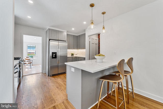 1604 Crittenden St NE, Washington, DC 20017 - kitchen with stainless steel fridge, gray cabinets, a peninsula, a kitchen breakfast bar, and light wood-style flooring