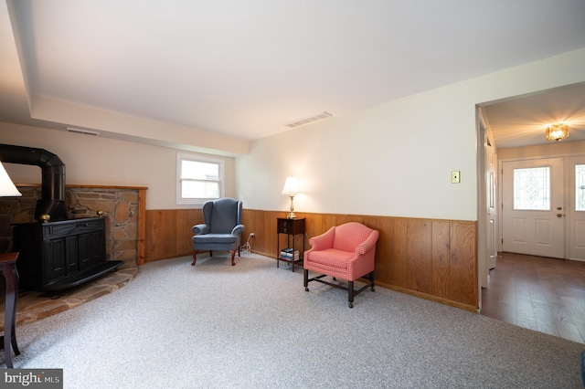 38 Gill Dr, Newark, DE 19713 - living area with a wainscoted wall, a wood stove, wood walls, carpet flooring, and wood finished floors