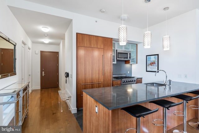 1414 S Penn Sq Unit 28A, Philadelphia, PA 19102 - kitchen featuring appliances with stainless steel finishes, brown cabinetry, a sink, a breakfast bar, and a peninsula