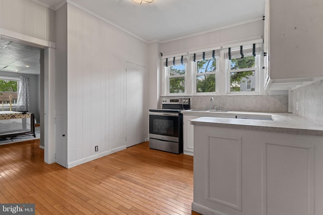 12 E Charles St, Palmyra, NJ 08065 - kitchen with stainless steel electric stove, light wood-style floors, light countertops, white cabinets, and tasteful backsplash