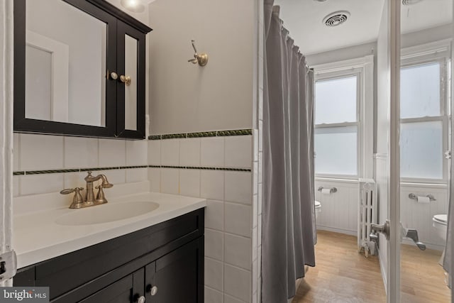 12 E Charles St, Palmyra, NJ 08065 - bathroom featuring vanity, radiator heating unit, wood finished floors, a wainscoted wall, and tile walls