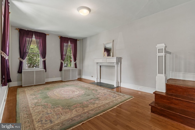 12 E Charles St, Palmyra, NJ 08065 - unfurnished living room with wood finished floors, stairs, a fireplace with flush hearth, and radiator