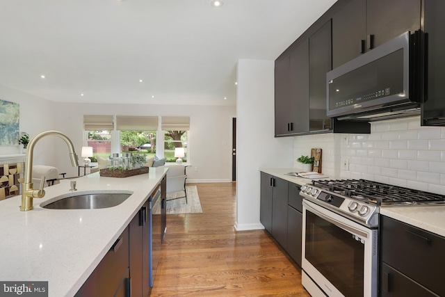 9309 E Parkhill Dr, Bethesda, MD 20814 - kitchen with stainless steel appliances, open floor plan, a sink, tasteful backsplash, and light wood-style floors