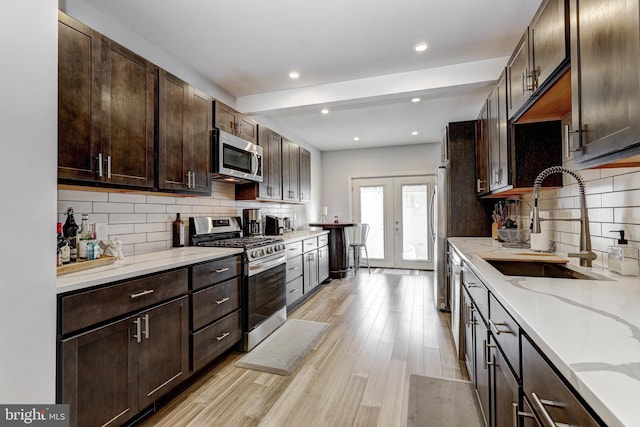 107 W Ostend St, Baltimore, MD 21230 - kitchen featuring appliances with stainless steel finishes, a sink, dark brown cabinets, decorative backsplash, and light wood finished floors