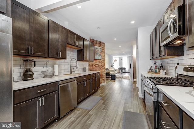 107 W Ostend St, Baltimore, MD 21230 - kitchen with appliances with stainless steel finishes, a sink, dark brown cabinetry, light wood-style floors, and recessed lighting